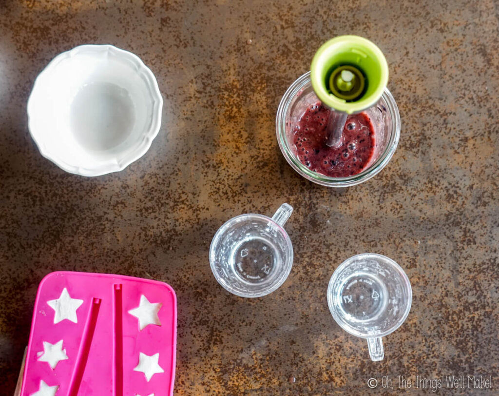 Overhead view of yogurt in star shaped trays and blueberry purée in a glass