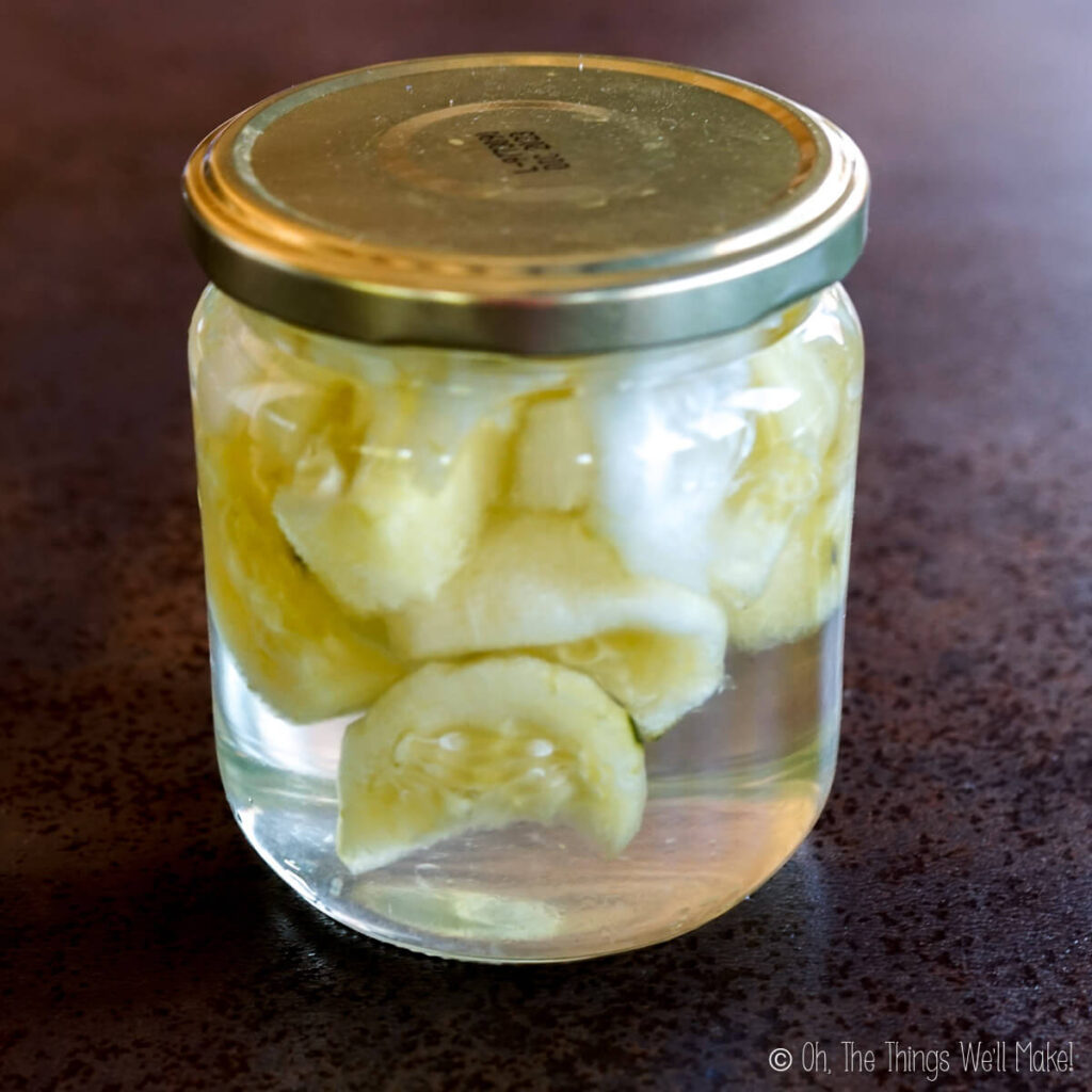 A jar with cucumber slices that have yellowed and shrivelled.