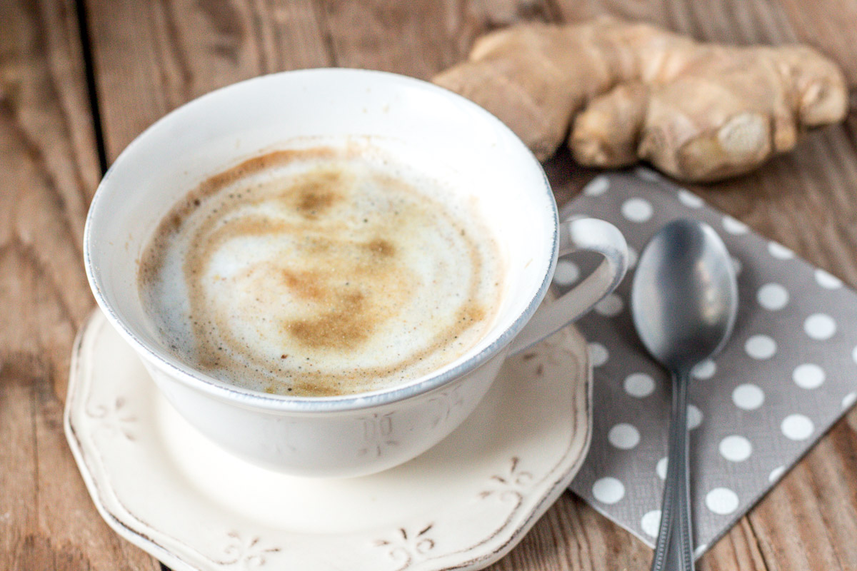 A cup of coffee in front of a ginger root.