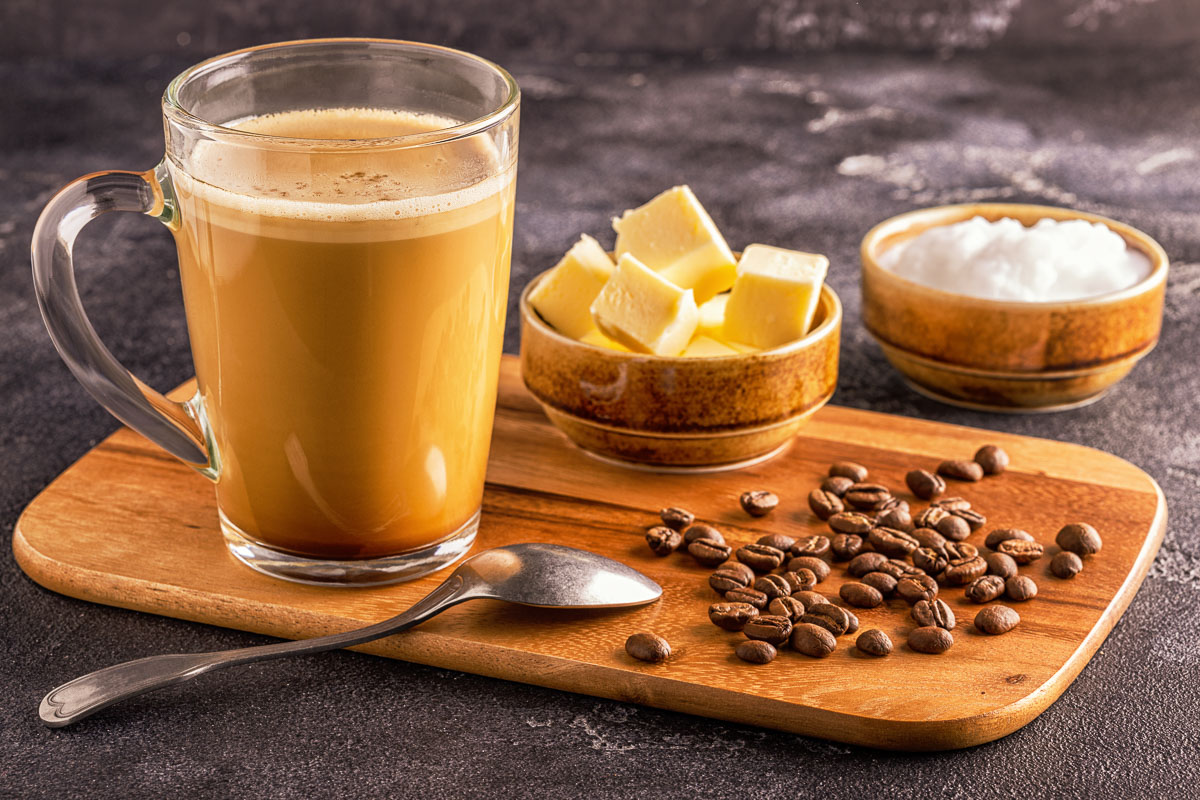 bulletproof coffee next to bowls of butter, solid oil, and coffee beans