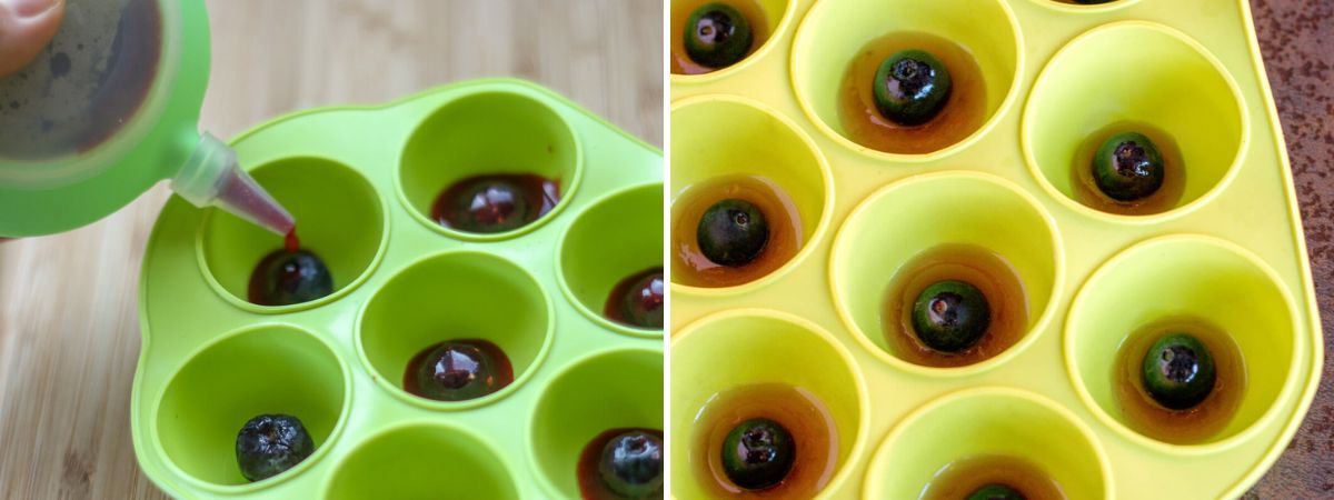Adding red fruit gelatin around blueberries in green silicone half-sphere molds to create the pupils and colored irises of homemade gummy eyeballs.