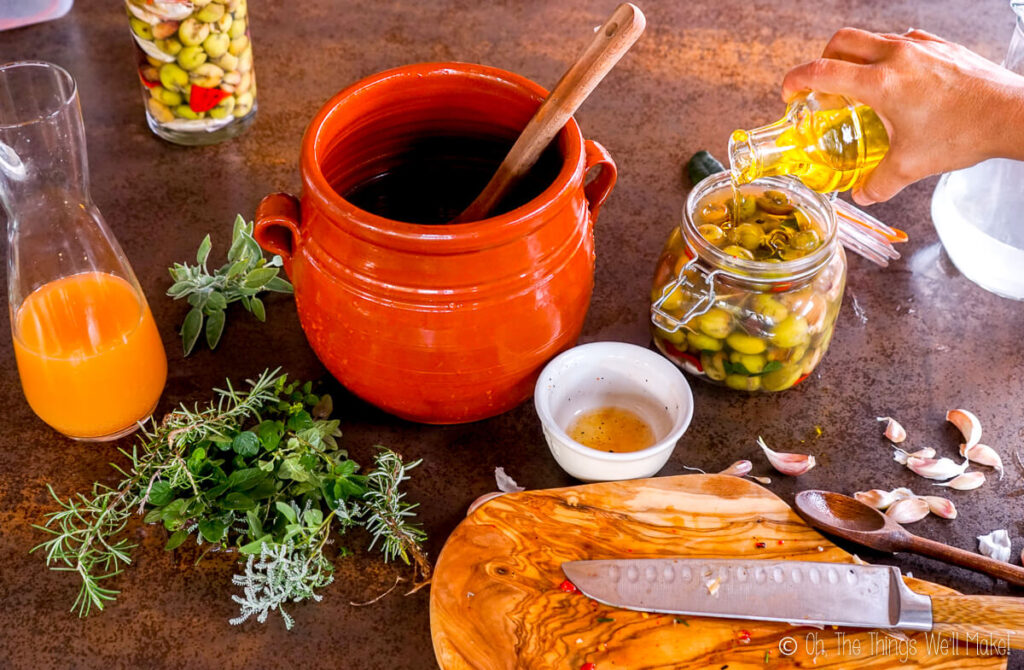 Pouring olive oil over olives in a jar