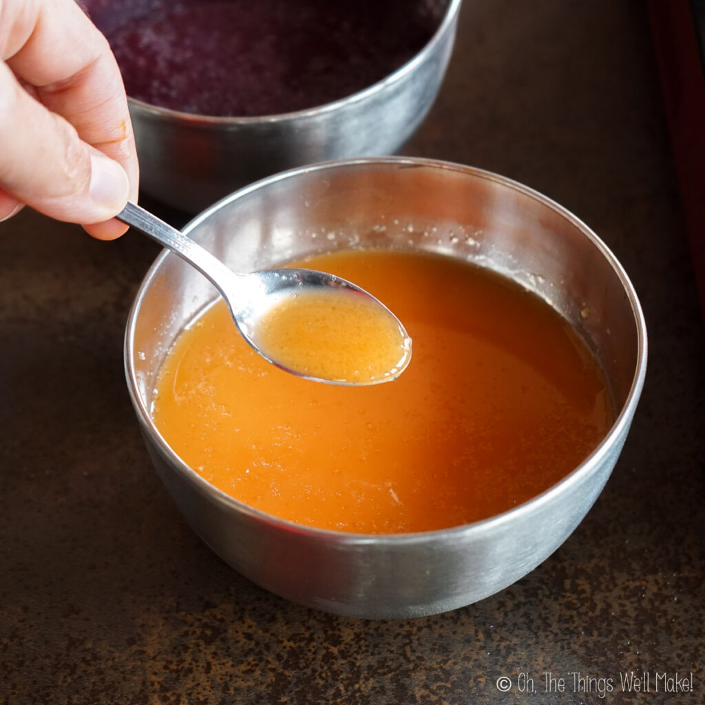 Holding up gelatin in a fruit juice on a spoon