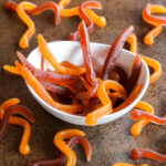 A bowl filled with orange and red homemade gummy worms