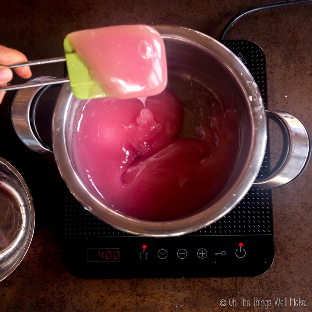 holding up a more thickened pink mixture on a spatula