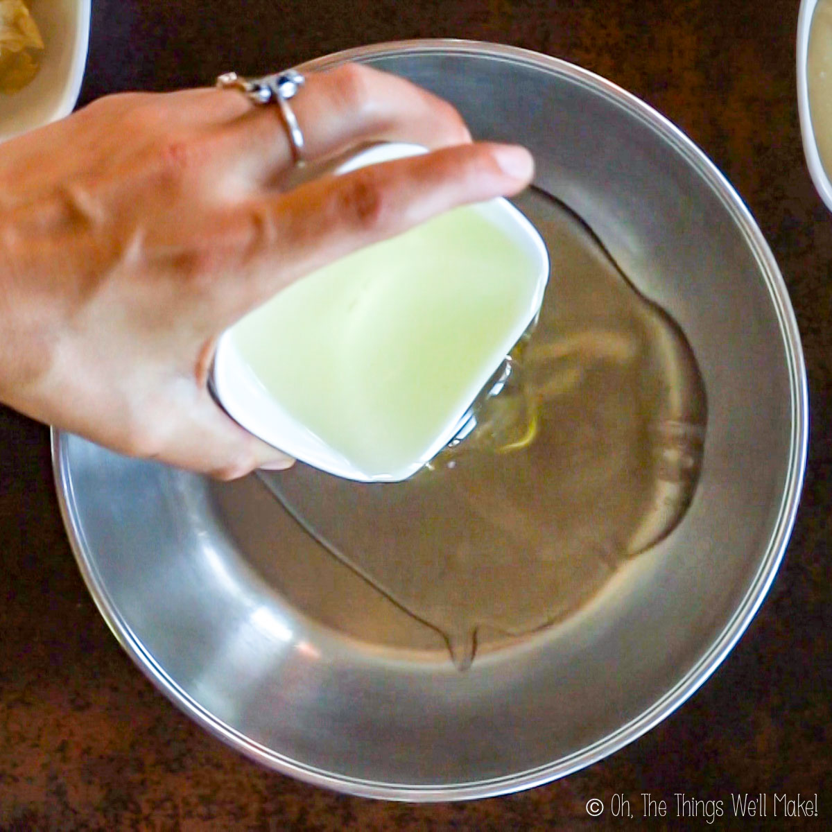 Pouring coconut oil into a stainless steel bowl