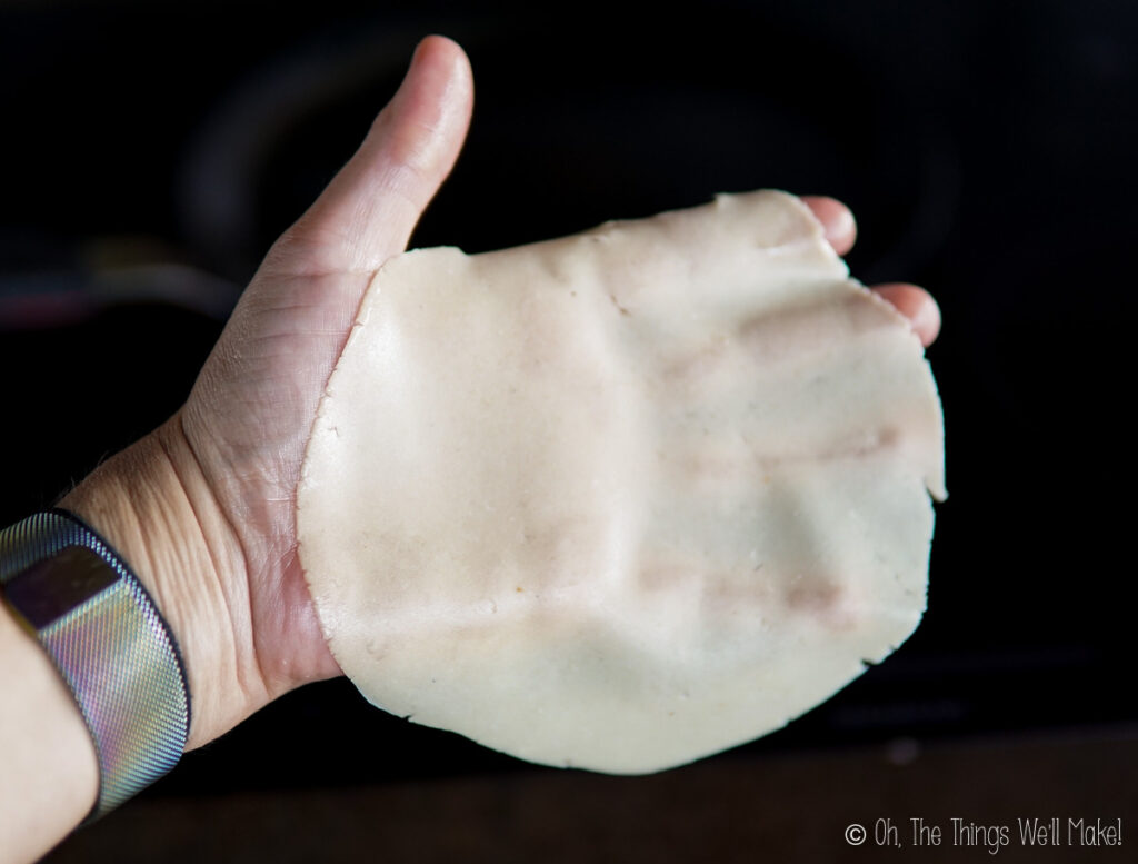 Holding a thin papadum dough disk over a hand