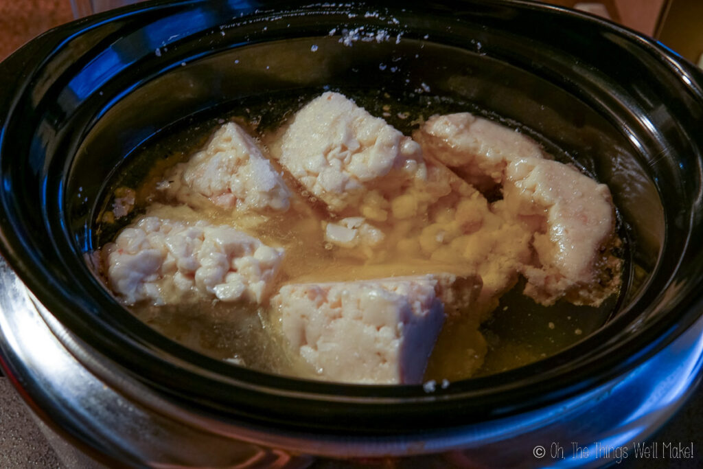 Beef fat being cooked and liquifying in a slow cooker.