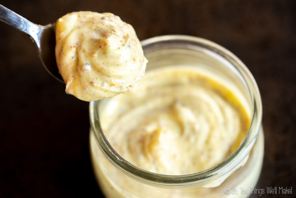 Whipped brown butter being held up in a spoon over a jar of whipped brown butter
