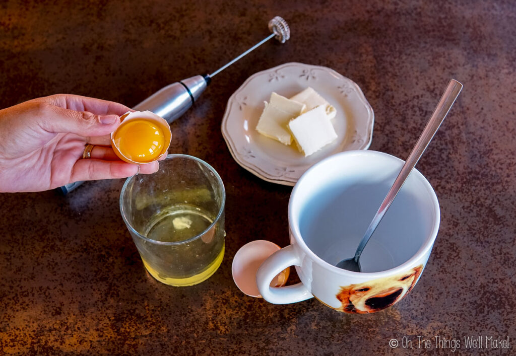 An egg white in an egg shell above a glass with an egg white.