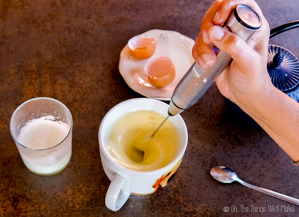 Mixing hot water with butter and an egg yolk with an egg frother.