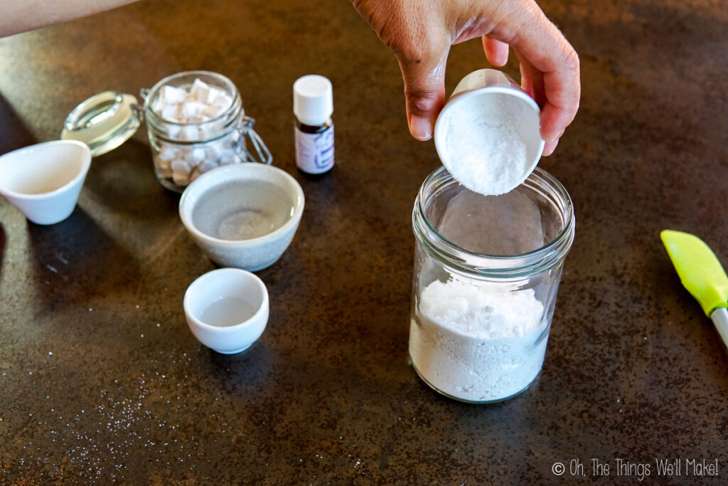 pouring xylitol into a glass jar with other dry ingredients