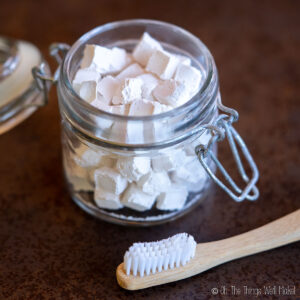 toothpaste tablets in a glass jar next to a toothbrush