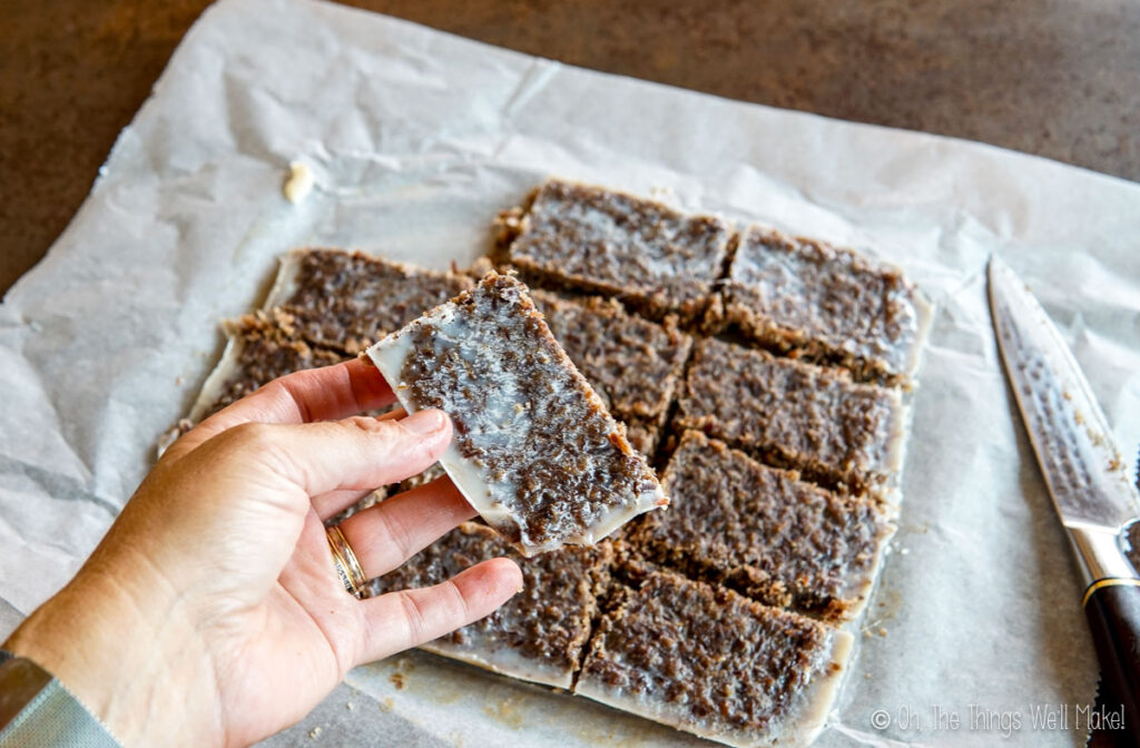 holding a pemmican bar over other cut bars