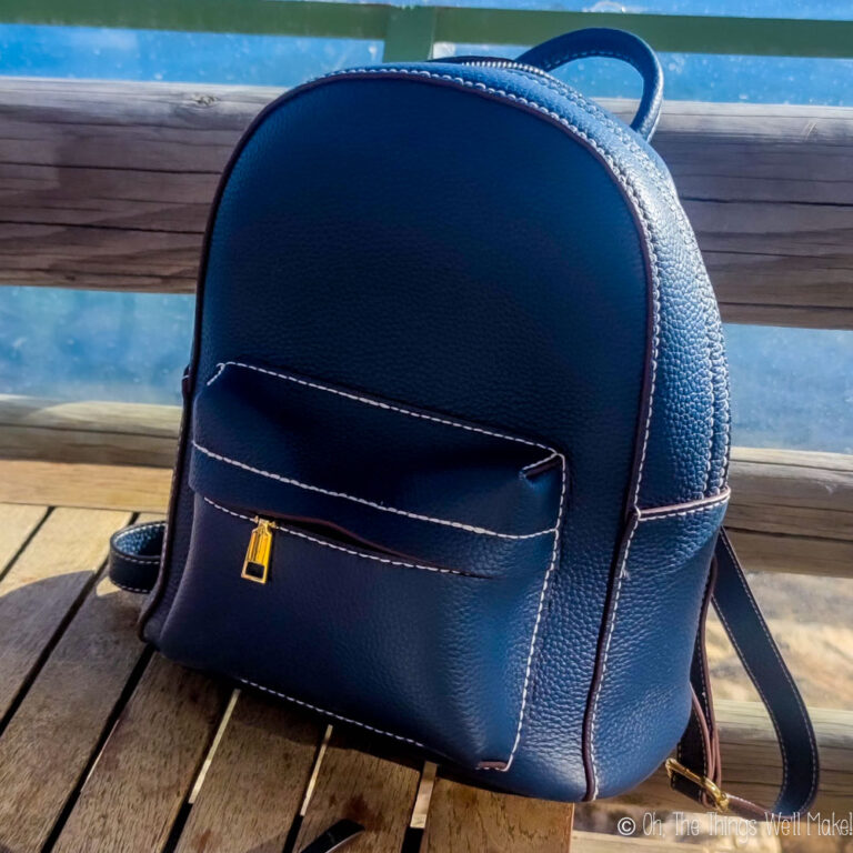 A blue leather backpack on a wooden table