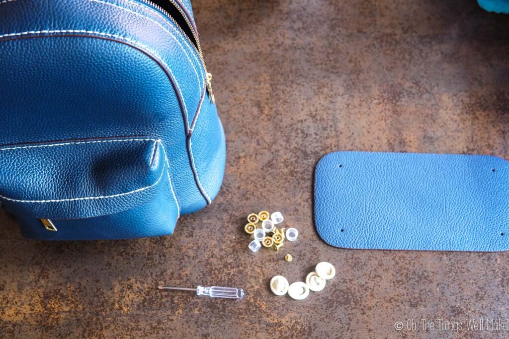 The bottom leather piece next to the metal feet and the backpack.