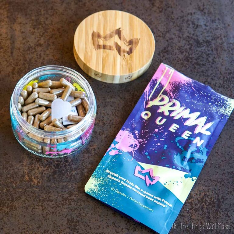 A glass jar of Primal Queen capsules next to the empty bag.