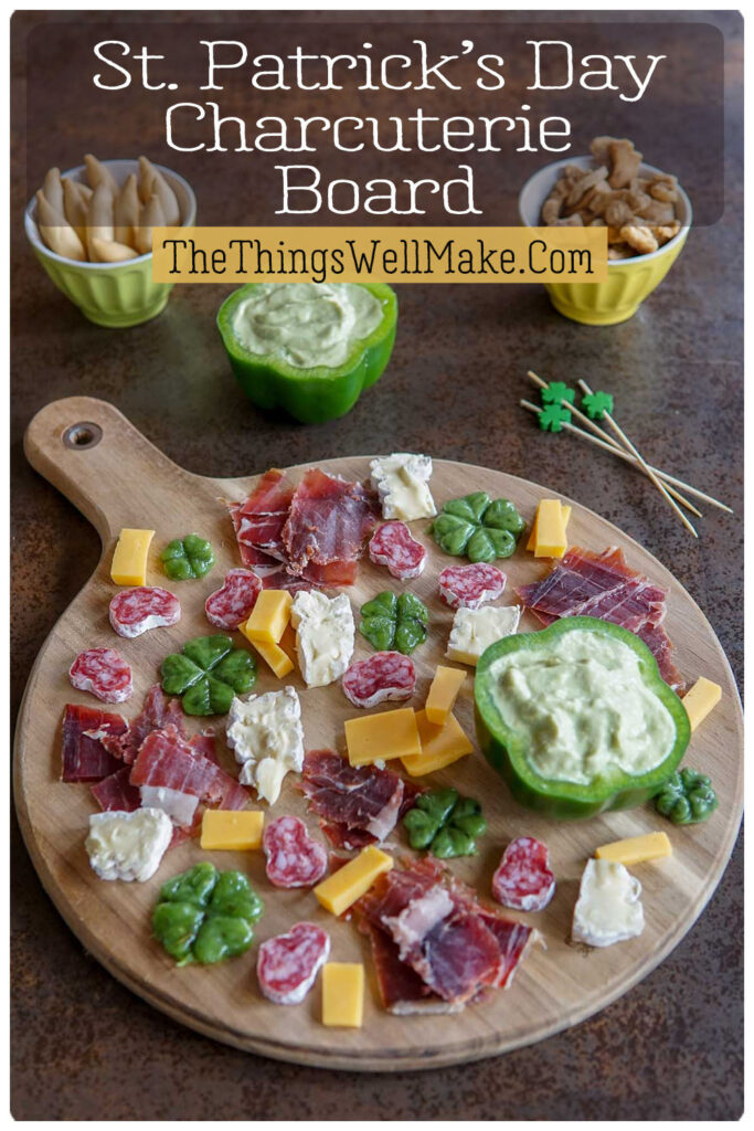 A festive St. Patrick's Day charcuterie board with meats, cheese, a green pepper “bowl” with avocado cream dip, and pork rinds. Served with themed picks.